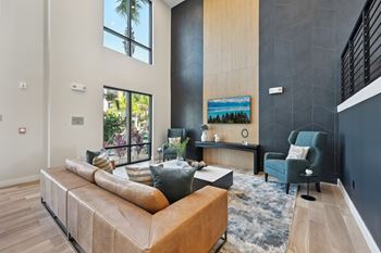 A modern living room with a large sectional sofa and a painting on the wall at The Concord Luxury Apartments, Sarasota